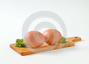Two brown eggs on cutting board
