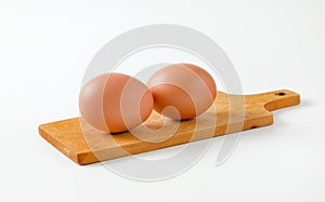 Two brown eggs on cutting board