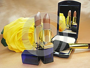 Two brown lipsticks powder and yellow rose