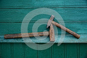 Two old hammers lie on a green wooden wall