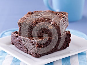 Two brownies stacked on a plate.