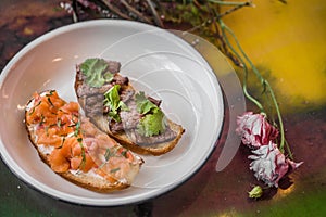 Two bruschetta on a white plate in a restaurant.