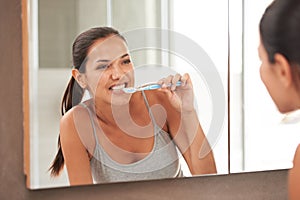 Two brushes a day keeps the dentist away. A portrait of a beautiful young woman brushing her teeth in her bathroom.