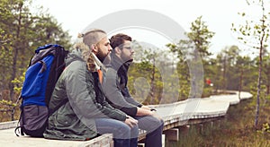 Two brutal, bearded men with backpacks sitting in swamps. Camp, adventure, traveling and trip concept.