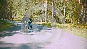 Two brutal motorcyclists in helmets riding their motorbikes in the coniferous forest