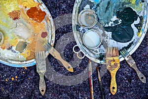 Two bucket lids as painter`s palettes with green yellow orange silicate paint and brushes on a painter`s fleece, copy space