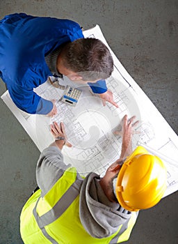 Two builders discuss construction blueprints