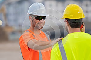 Two builders in a hard hat is busy working on a construction project at a site. A builders workes in a helmet near