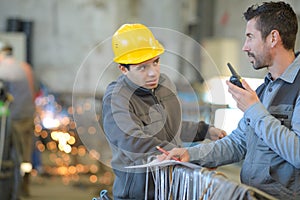 Two builders in helmets working with walkie talkie