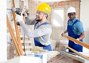 Two builders working on indoor construction site