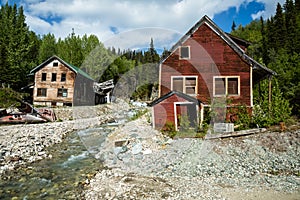 Two buildings standing and one collapsed by river in old abandon