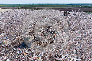 Two bulldozer working on mountain of garbage in landfill
