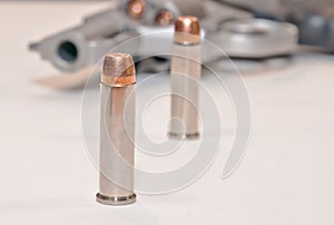 Two bullets in front of a loaded revolver