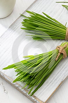 Two bundles of fresh barley grass on a white table