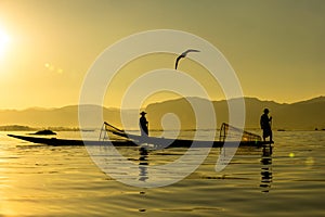 Two Burmese men paddle their legs Came out to find fish in the morning on Inle Lake