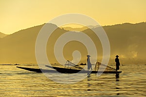 Two Burmese men paddle their legs Came out to find fish in the morning on Inle Lake