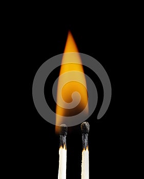 Two burning matchsticks against a black background