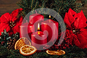 Two burning Red advent candles in advent wreath decoration on wooden dark background