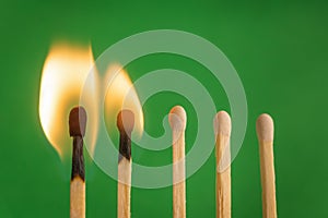 Two burnt match in set of matchsticks on green background. Selective focus