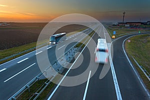 Two buses in motion blur on the highway at sunset