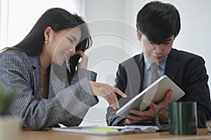 Two business associates using digital tablet and working together in office.