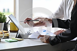 Two business colleagues analyzing financial data on computer tablet together.