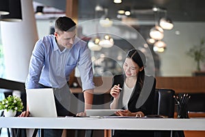 Two business colleagues checking financial reports and discussing project together.