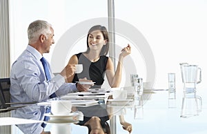 Two Business Colleagues Sitting Around Boardroom Table Having In