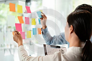 Two business executive team holding and taking notes keyword on board wall to brainstorm about a new business project for planning