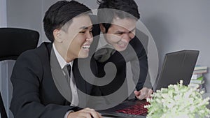 Two business man laughing while using a laptop computer