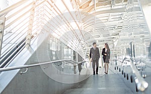 Two business man and woman talking and walking outside