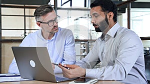 Two business men analysts discussing data management using laptop computer.