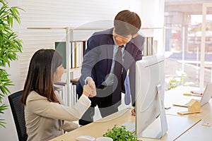 Two business men and business women shake hands in the office meeting with a smiling face