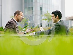 Two Business Men Enjoying Lunch Break Eating Sandwich Outdoors