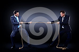 Two business men pulling rope in a competition