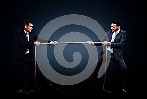 Two business men pulling rope in a competition