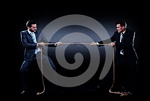 Two business men pulling rope in a competition, isolated on white background.