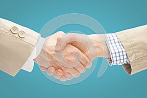 Two business men shaking hands - close up studio shot on light blue background