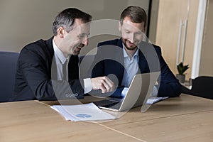 Two business partners discuss on-line project using laptop