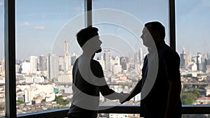 Two business partners do handshake in front of view on downtown and skyscrapers. A good business deal, shake hands with