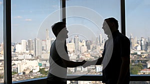 Two business partners do handshake in front of view on downtown and skyscrapers. A good business deal, shake hands with