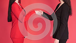 Two business partners shaking hands in agreement on red background.