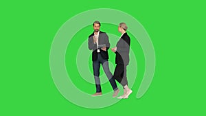 Two business partners walking using tab and talking to each other on a Green Screen, Chroma Key.