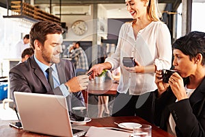 Two business people with laptop paying in a coffee shop