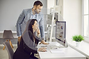 Two business people looking at graphs and charts on the computer screen in the office