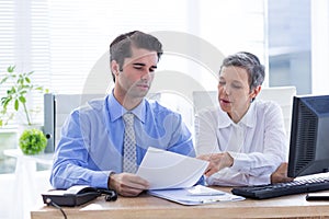 Two business people looking at a paper while working on folder