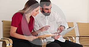 Two business people man and a woman, are having discussion reading financial report together in office lobby