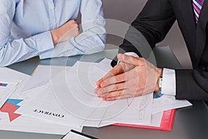 Two business people negotiating sitting at table in office.