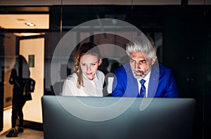 Two business people in an office at night., working.