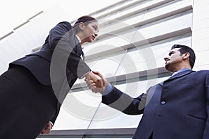 Two business people shaking hands outside office